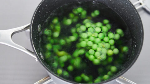 Boiling green peas in salted water for making green pea pesto.