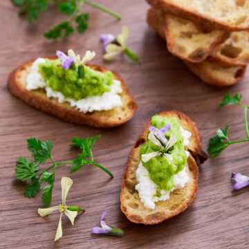 Welcome spring with this Perfect Pea Pesto spread of crisp crostini and garnished with argugula and sage blossoms.