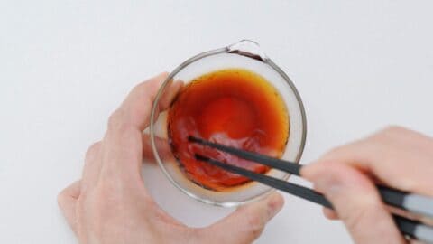 Mixing Traditional Gyoza Sauce in a glass bowl with chopsticks.