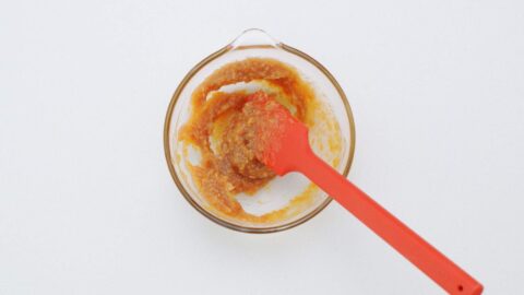 Mixing miso, honey and grated ginger in a glass bowl.