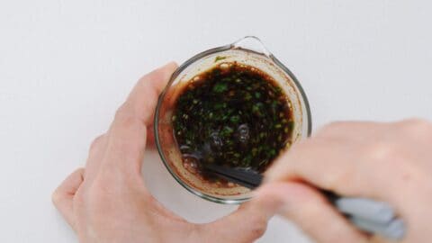 Mixing black vinegar, soy sauce, Chinese five spice, and cilantro together.