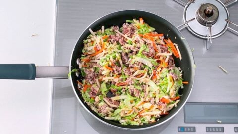 Vegetables and meat stir-frying for making Japanese spring rolls.