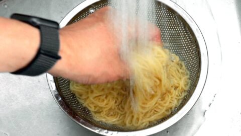 Washing boiled ramen noodles under cold running water.