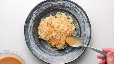 Dressing chilled ramen noodles with sesame dressing.