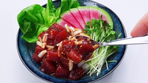 Spooning Poke onto rice bowl.