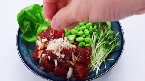 Garnishing Poke Bowl with crunchy inamona.