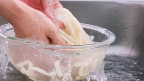 Washing boiled udon noodles in cold water.