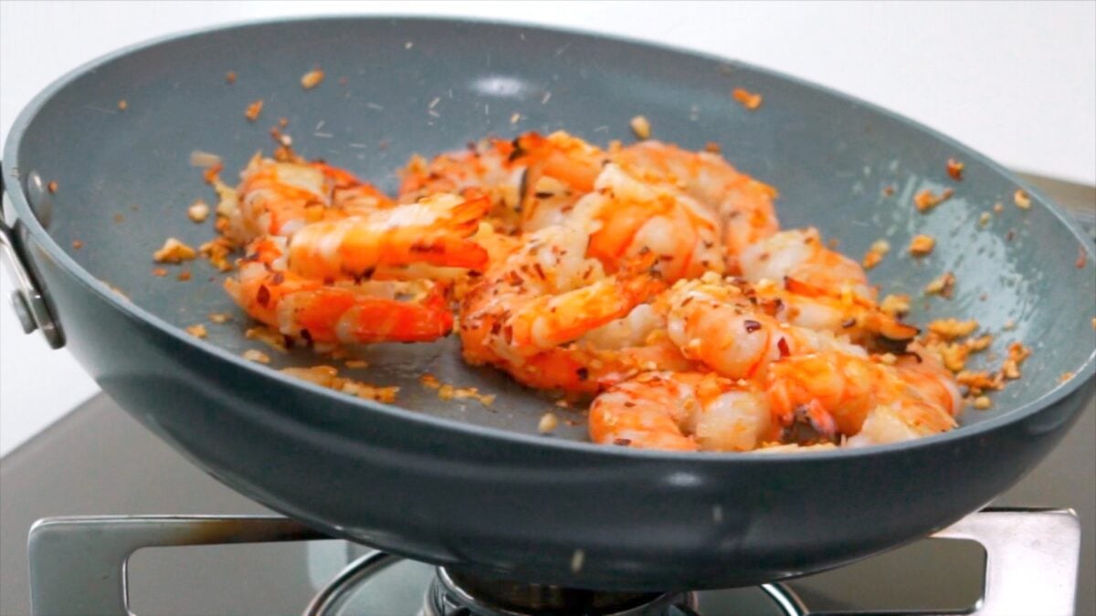 Tossing shrimp and garlic in a plan.