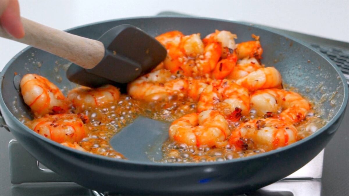 Honey garlic sauce caramelizing around shrimp in a pan.