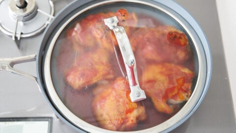 Honey lemon chicken in a frying pan, covered with a lid.