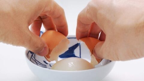 Cracking hot spring egg into a small bowl.