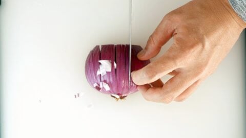 Cutting vertical slits in an onion.