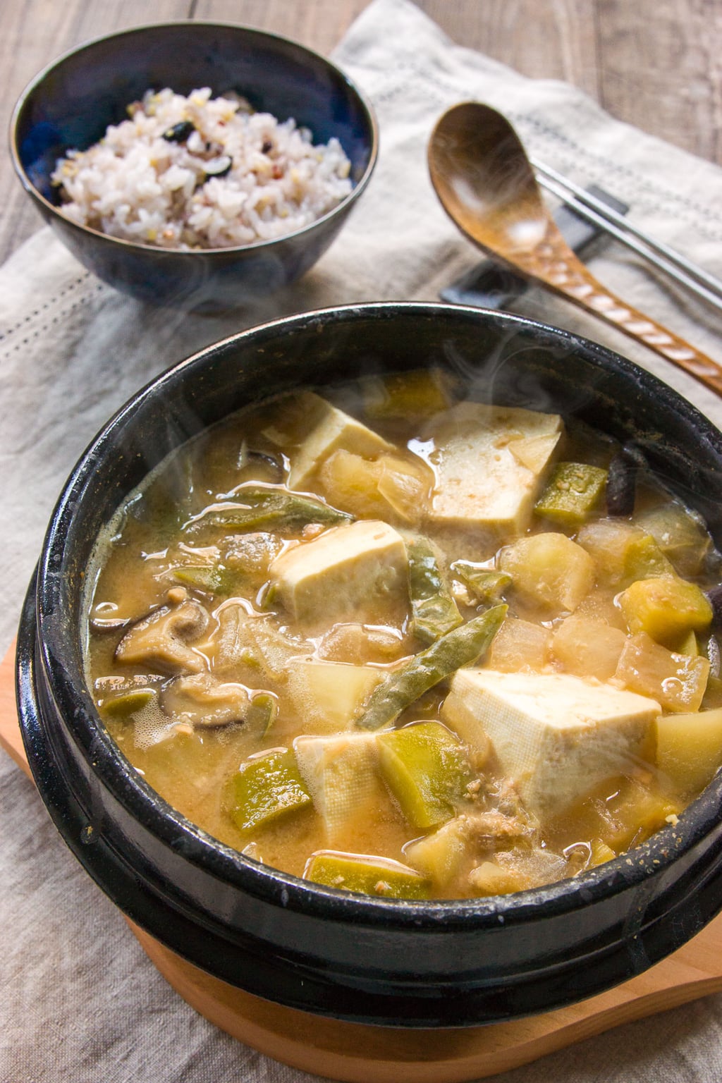 Doenjang Jjigae, is a hearty Korean stew loaded with vegetables, mushrooms and garlic and redolent of garlic. Seasoned with a fermented bean paste, it has an nutty funk that gives the soup a marvelous earthy flavor.