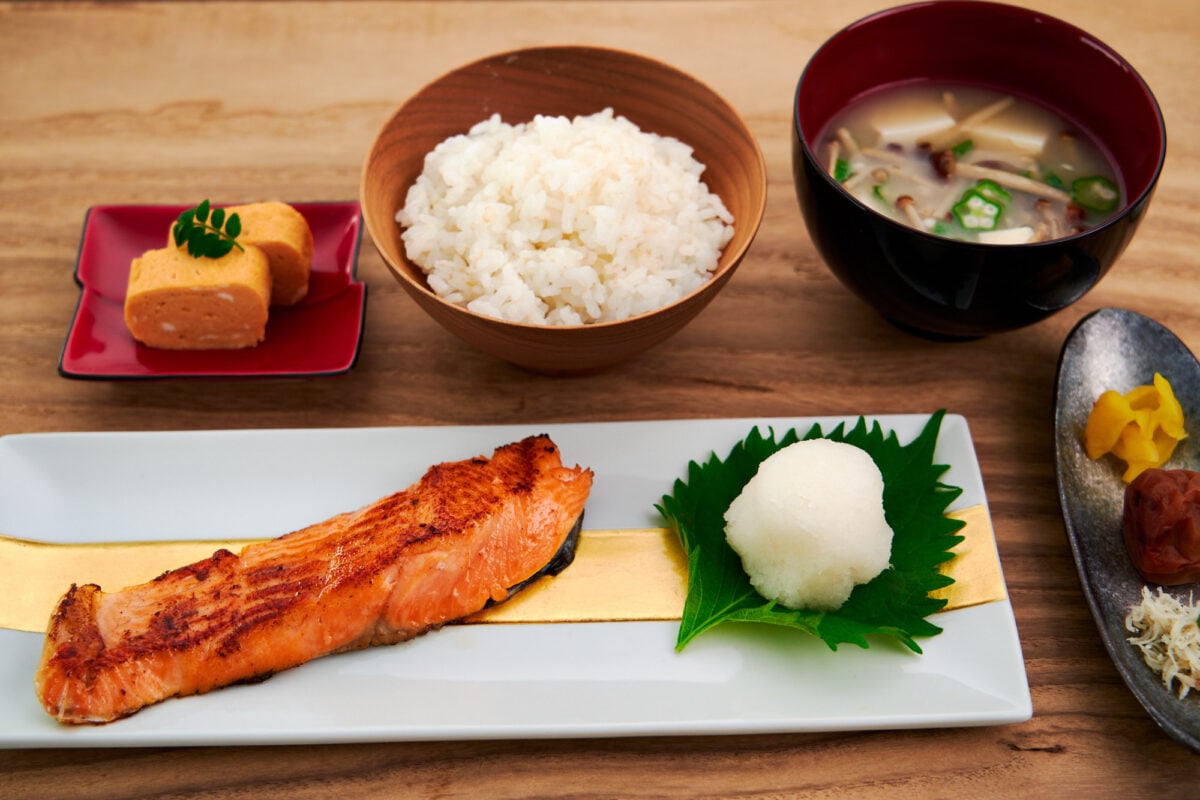 Salt-cured salmon or Shiozake is a staple of traditional Japaense breakfasts, shown here with tamagoyaki, rice, miso soup, and pickles.