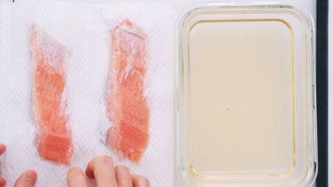 Using paper towels to pat the brined salmon dry.