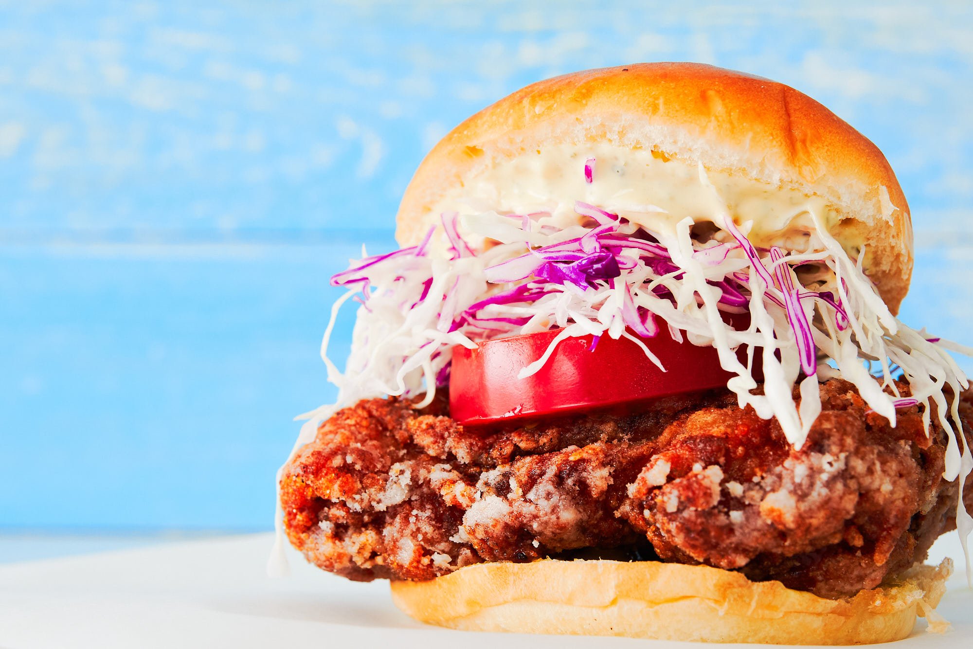 Japanese chicken sandwich stuffed with shatteringly crisp chicken karaage shredded cabbage and tomato between a butter roll slathered with yuzu mayonnaise.