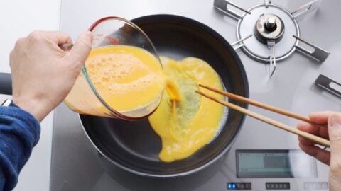 Pouring dashimaki tamago mixture into a hot frying pan.