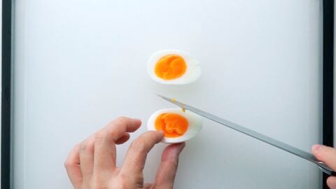 Cutting a medium boiled egg in half for a sandwich.