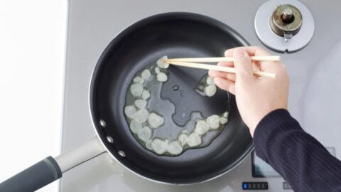 Frying sliced garlic in oil to make garlic chips.