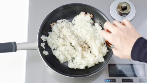 Adding soy sauce to the rim of the pan.