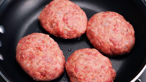 Raw hamburg steaks in a frying pan.