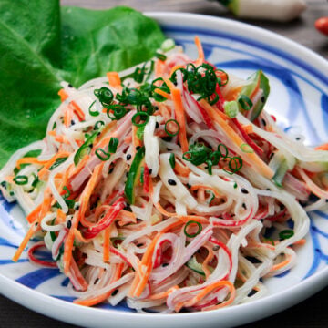 A plate of kani salad made with crab sticks, cucumber, and carrots in a creamy lemon dressing.