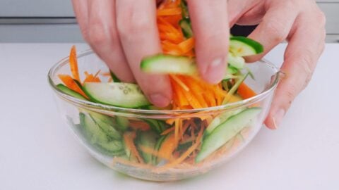 Tossing carrots and cucumbers with salt.