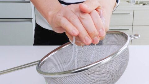 Squeezing water out of rehydrated glass noodles.