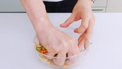 Squeezing carrots and cucumbers to remove excess water.