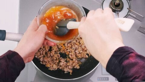 Stirring Mapo Tofu sauce and adding it to the pan.