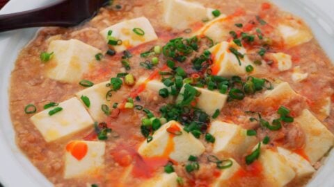 Mapo Tofu garnished with chili oil and scallions.