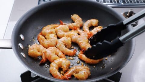 Flipping shrimp over in a frying pan.