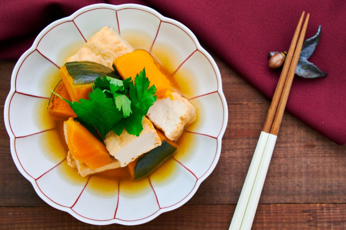 Bowl of Kabocha no Nimono or "simmered kabocha" with cubes of kabocha squash and atsuage tofu.