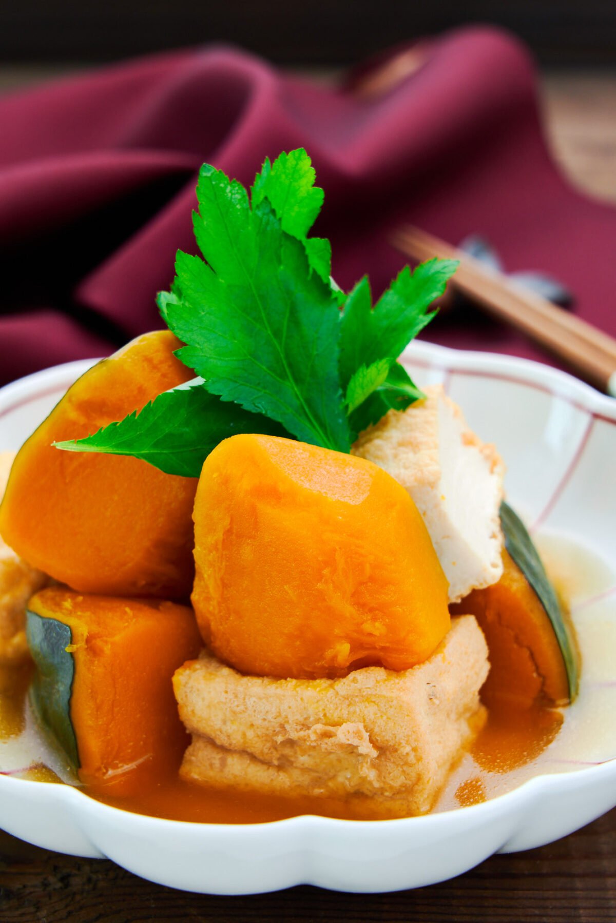 Creamy sweet cubes of kabocha squash simmered with atsuage tofu and dashi garnished with mitsuba.