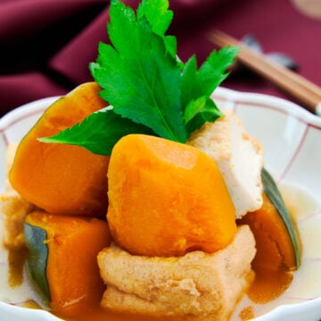 Creamy sweet cubes of kabocha squash simmered with atsuage tofu and dashi garnished with mitsuba.