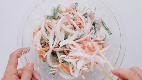 Tossing onions, carrots maitake, and green beans with flour to make tempura.