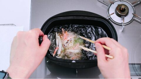 Adding kakiage tempura fritter to hot oil to deep-fry.