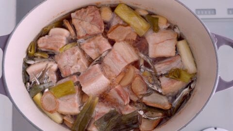 Braised pork belly with ginger, and scallions in a dutch oven.