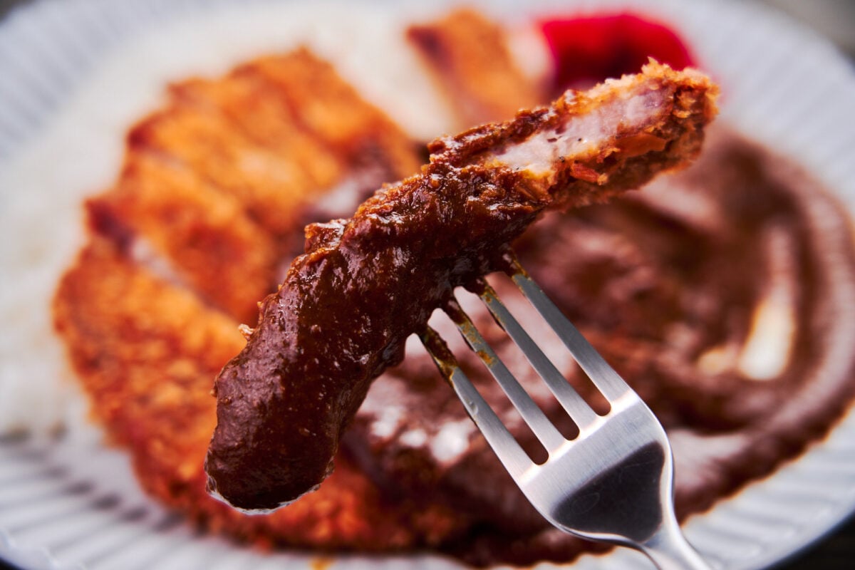 A slice of crispy pork katsu enrobed in spicy Japanese curry sauce.