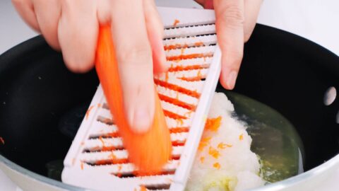 Grating carrots and onions into a pan for making Japanese curry sauce.