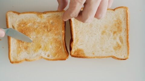 Spreading spicy mustard on toasted bread is the first step for assembling a Katsu Sandwich.