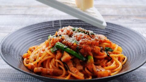 Grating cheese onto kimchi pasta.