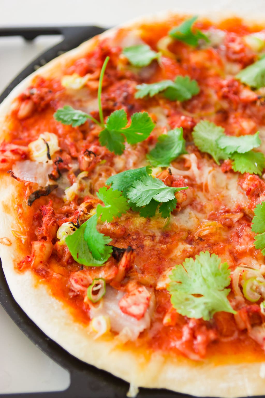 Scrumptious kimchi pork belly pizza with gruyere cheese and a spicy gochujang sauce. 