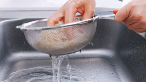 Draining and rinsing julienned burdock root.