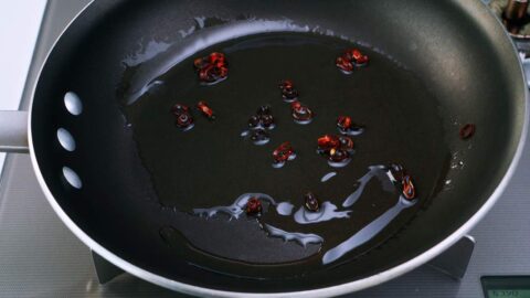 Red chili peppers and oil in a frying pan.