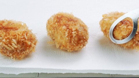 Draining fried potato croquettes on paper towels.