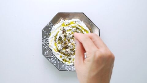 Sprinkling za'atar over Labneh.