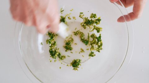 Mixing salt, vinegar and cilantro to make sauce for French fries.