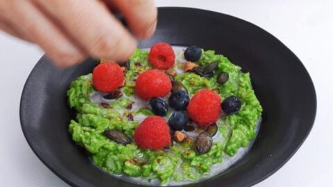 Topping matcha oatmeal with berries.