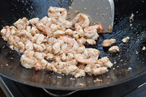 Chicken is added to the spices in a wok